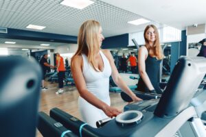 Mother and teen daughter in sportswear exercise on treadmill at the gym