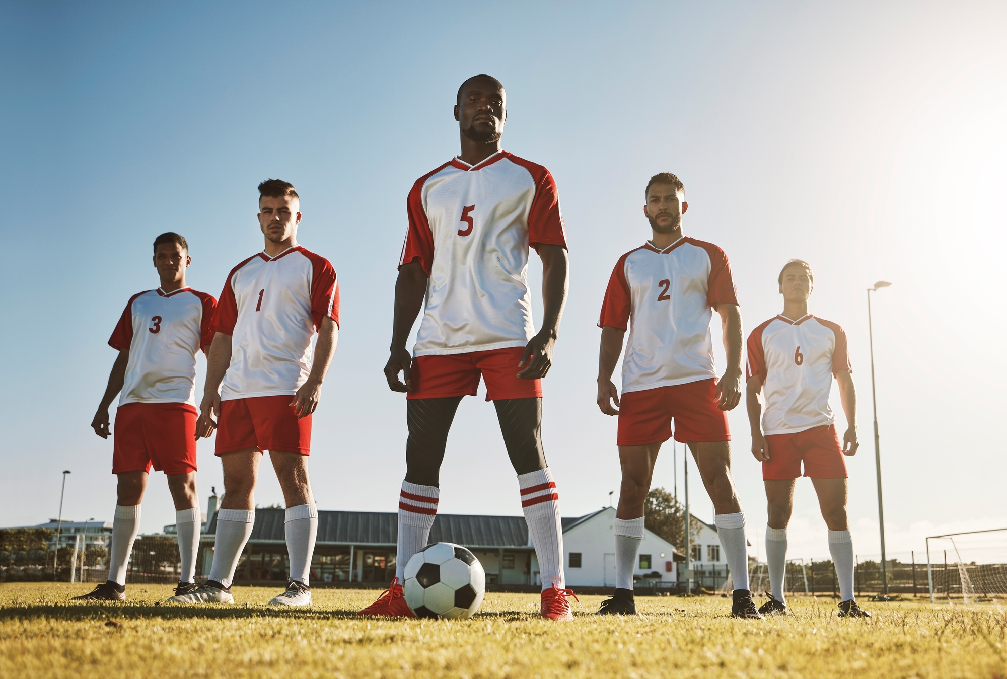 Soccer player, team and sports training on soccer field by men standing with ball, power and strong