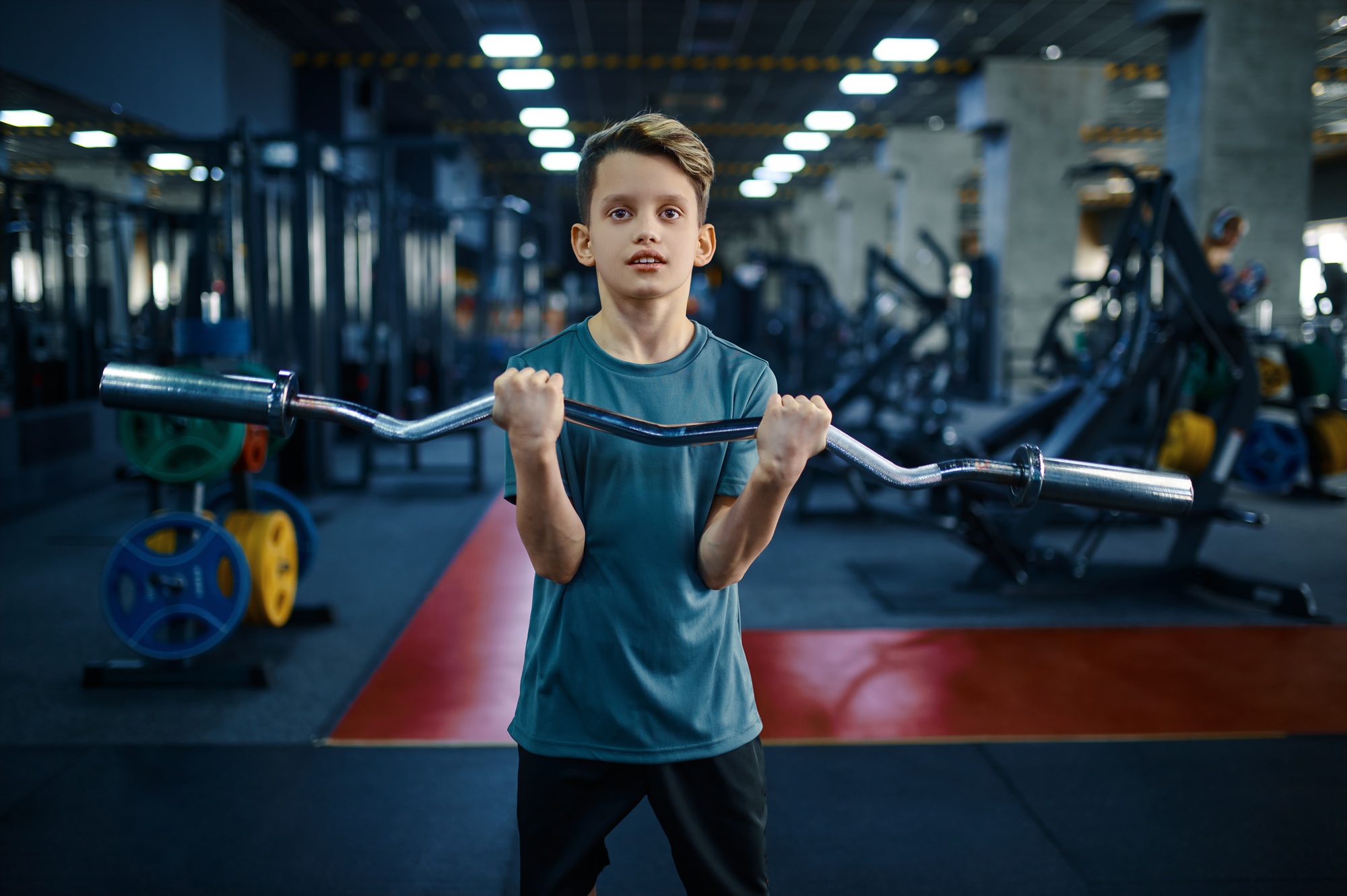 Youngster doing exercise with bar in gym