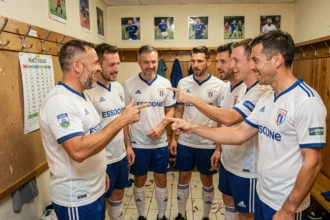 Joueurs de football amateur en Essonne consultant le calendrier des championnats FFF 2026 dans un vestiaire de club
